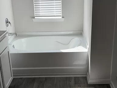 bathroom featuring wood-type flooring, vanity, and a bath to relax in