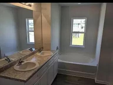 bathroom featuring dual sinks, a bath to relax in, and large vanity