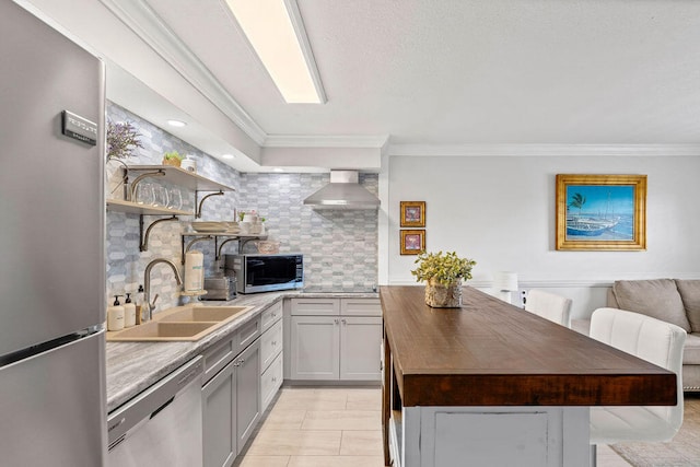 kitchen with appliances with stainless steel finishes, tasteful backsplash, wall chimney exhaust hood, sink, and light tile floors