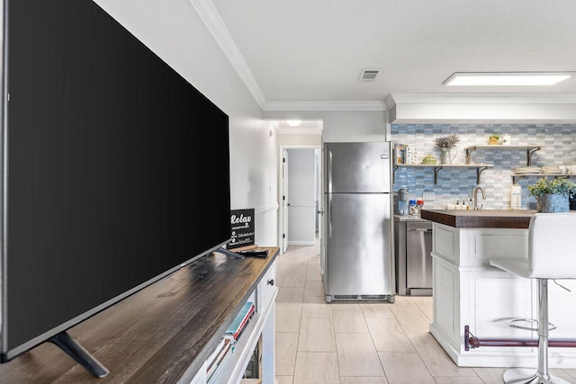 kitchen featuring tasteful backsplash, white cabinetry, stainless steel appliances, and crown molding