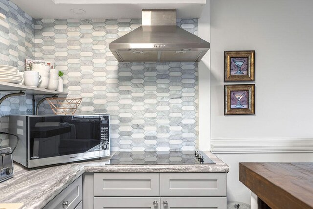 kitchen with wall chimney exhaust hood, tasteful backsplash, and black electric cooktop