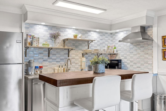 kitchen with wall chimney range hood, tasteful backsplash, stainless steel appliances, and crown molding