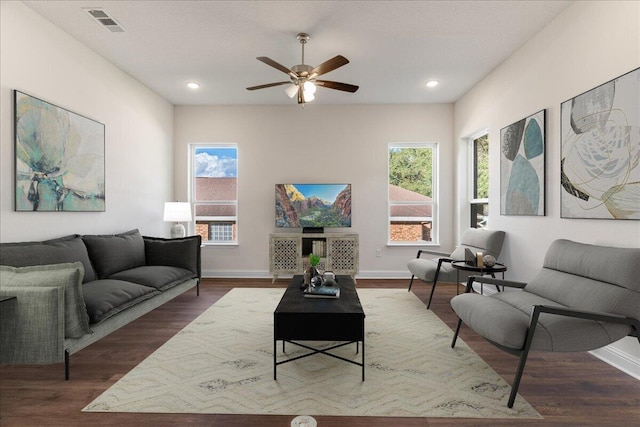 living room with dark hardwood / wood-style flooring, ceiling fan, and plenty of natural light