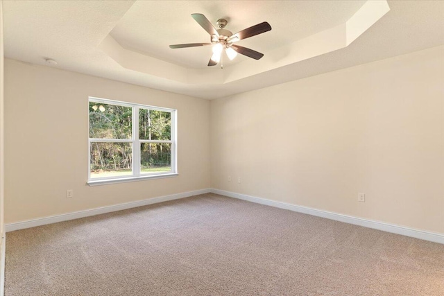 unfurnished room featuring carpet, ceiling fan, and a raised ceiling