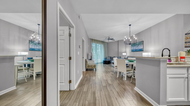 kitchen with ceiling fan with notable chandelier, light hardwood / wood-style floors, decorative light fixtures, and white cabinets