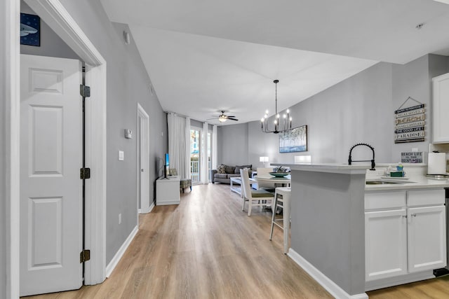 kitchen with white cabinetry, light wood-style floors, open floor plan, light countertops, and pendant lighting