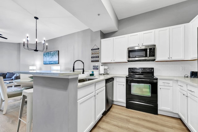 kitchen with stainless steel appliances, a peninsula, light countertops, and white cabinetry