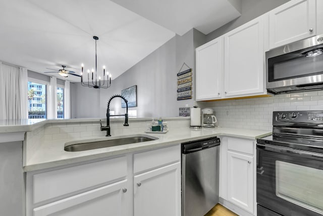 kitchen featuring stainless steel appliances, a sink, white cabinetry, hanging light fixtures, and backsplash