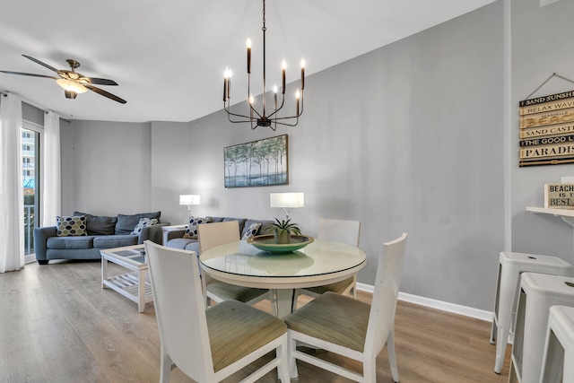 dining room with wood finished floors, a ceiling fan, and baseboards