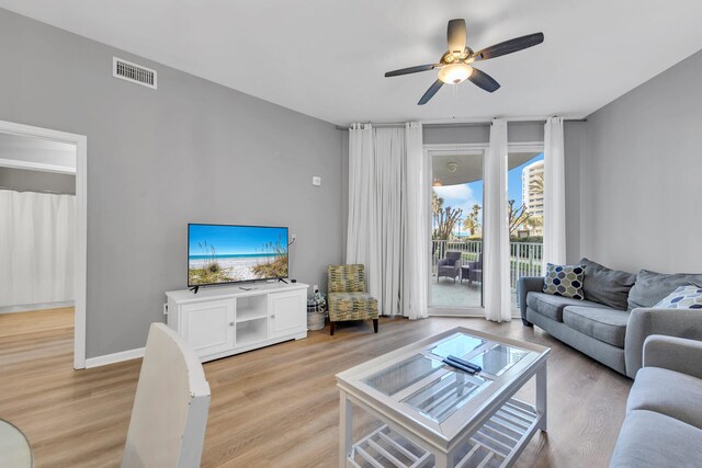 living room with light wood finished floors, baseboards, visible vents, and a ceiling fan