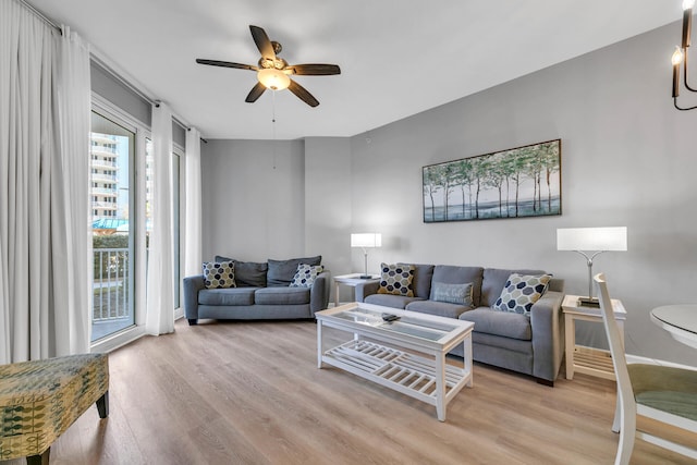 living room featuring light wood-style floors, baseboards, and a ceiling fan