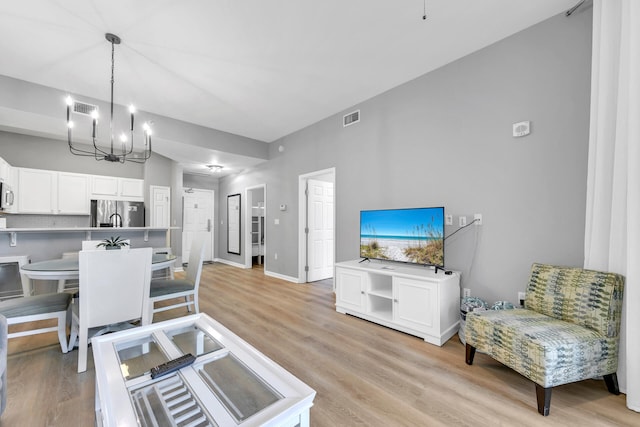 dining space featuring baseboards, an inviting chandelier, visible vents, and light wood-style floors