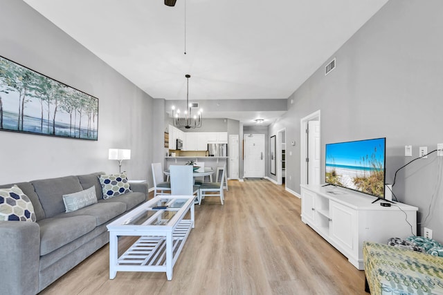 living room featuring a notable chandelier, baseboards, visible vents, and light wood-style floors