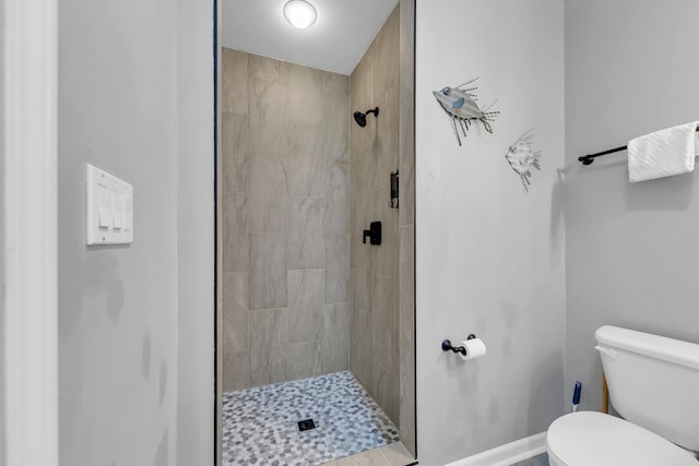 full bath with baseboards, a shower stall, and toilet