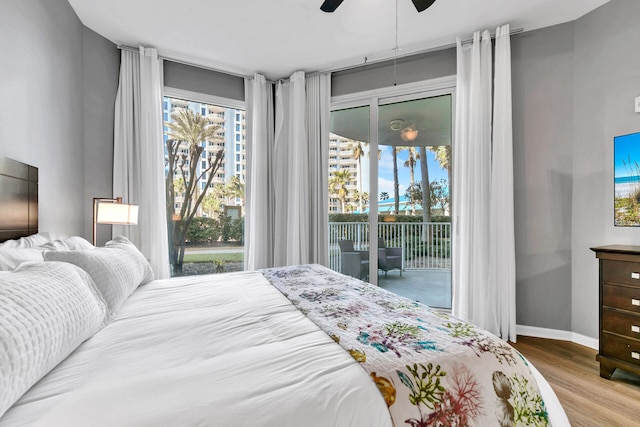 bedroom featuring access to outside, multiple windows, wood finished floors, and baseboards