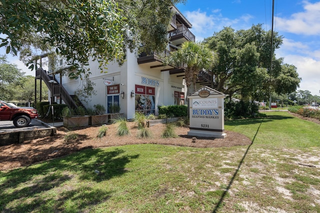 view of front of property featuring a balcony and a front yard