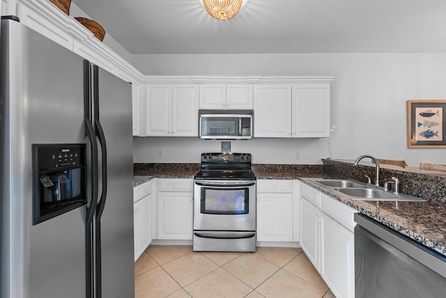 kitchen featuring stainless steel appliances, dark stone counters, white cabinets, sink, and light tile floors