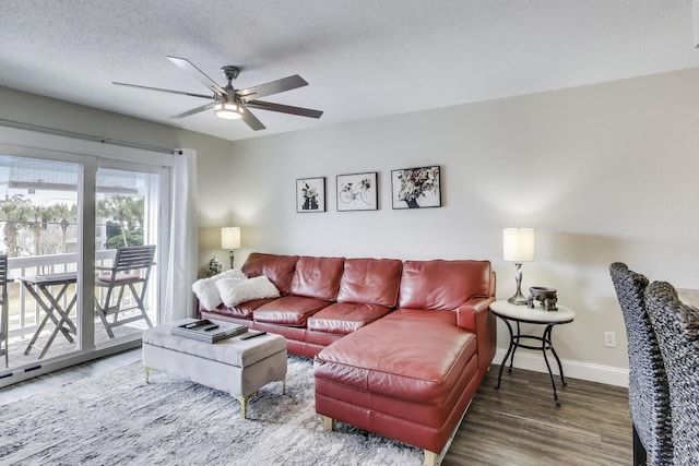 living area with a ceiling fan, a textured ceiling, baseboards, and wood finished floors