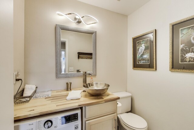 bathroom with toilet, washer / dryer, and vanity