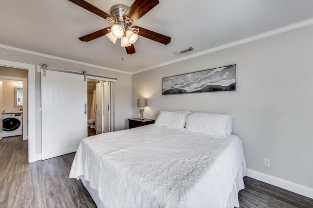 bedroom featuring visible vents, a barn door, dark wood-type flooring, washer / dryer, and baseboards