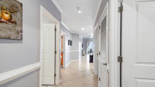 hallway with ornamental molding and light tile floors