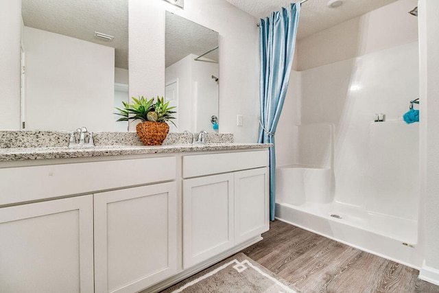 bathroom with vanity, hardwood / wood-style floors, a textured ceiling, and curtained shower