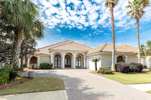 mediterranean / spanish home featuring a garage and a front lawn