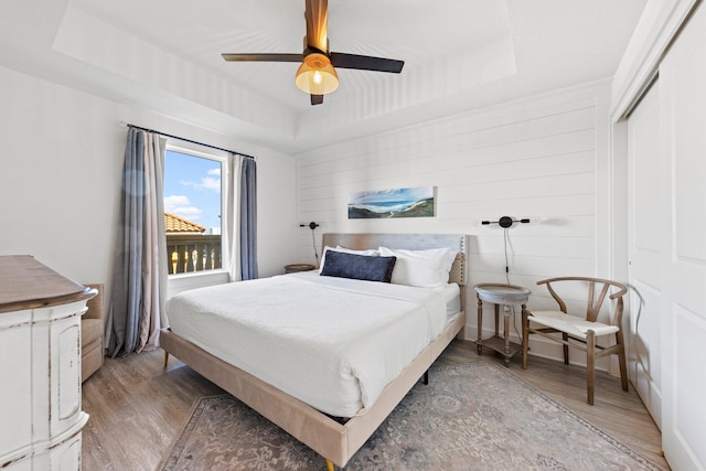 bedroom featuring wood-type flooring, ceiling fan, a raised ceiling, and a closet