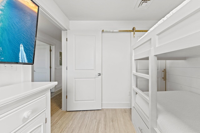 walk in closet featuring light wood-type flooring and a barn door