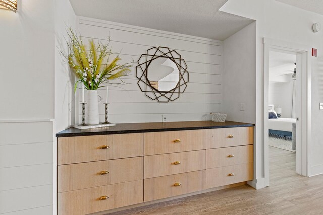 interior details with light hardwood / wood-style flooring, ceiling fan, vanity, and a textured ceiling