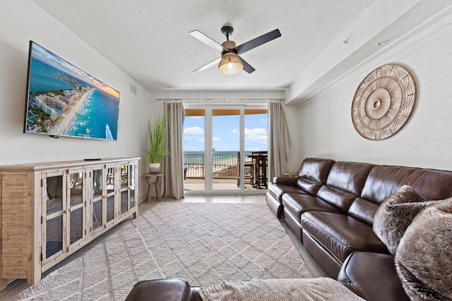 living room featuring ceiling fan and a textured ceiling