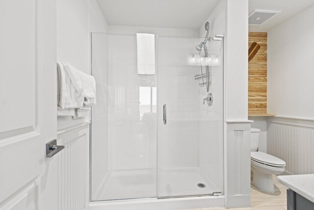 bathroom with a shower with door, vanity, and toilet