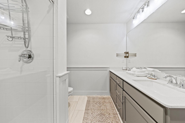 bathroom with a shower, tile floors, double vanity, toilet, and a textured ceiling