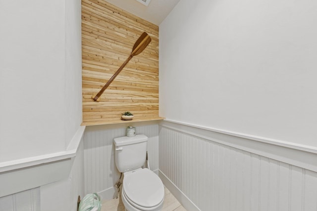 bathroom with wood walls and toilet