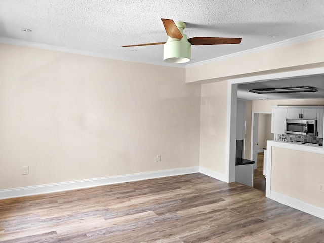 unfurnished room featuring ceiling fan, crown molding, a textured ceiling, and hardwood / wood-style floors