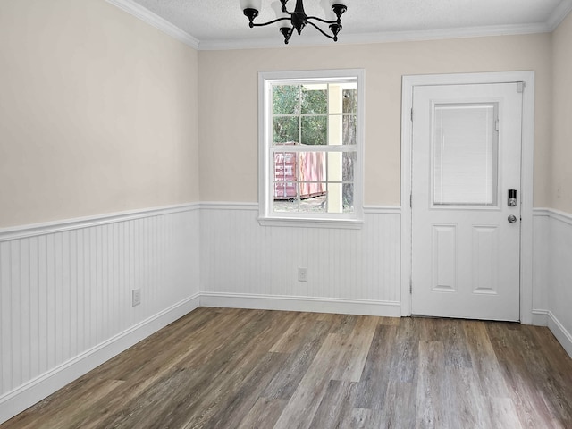 interior space with a notable chandelier, a textured ceiling, hardwood / wood-style floors, and crown molding