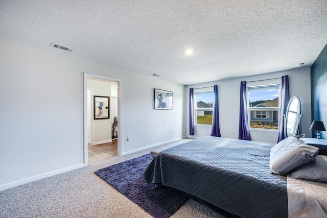 carpeted bedroom featuring a textured ceiling and ensuite bath