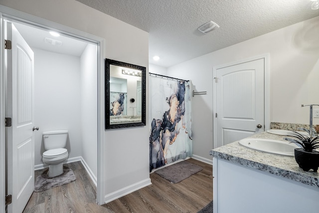 bathroom with hardwood / wood-style floors, vanity, a textured ceiling, and toilet