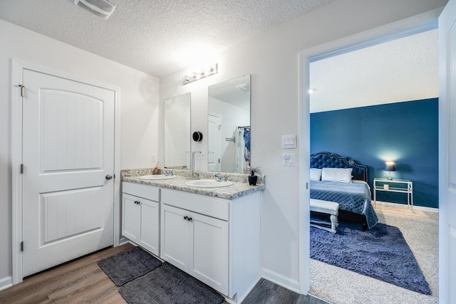 bathroom featuring hardwood / wood-style floors, vanity, and a textured ceiling