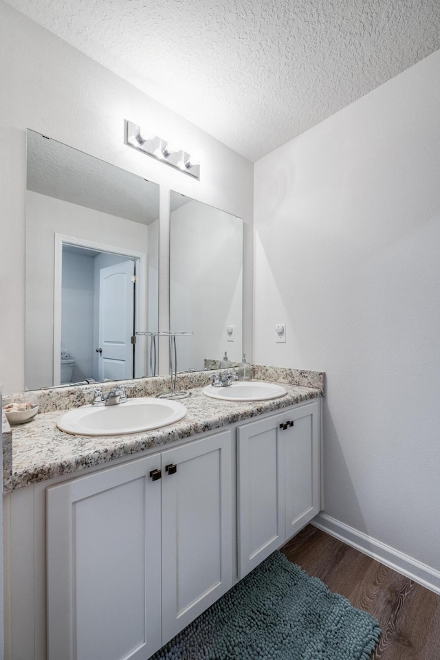 bathroom featuring toilet, vanity, a textured ceiling, and hardwood / wood-style flooring