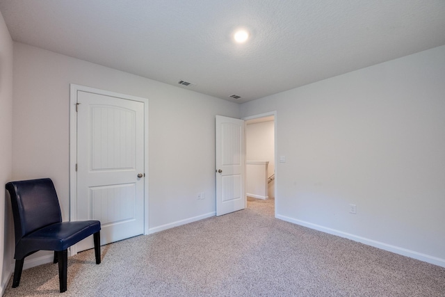 living area with light carpet and a textured ceiling