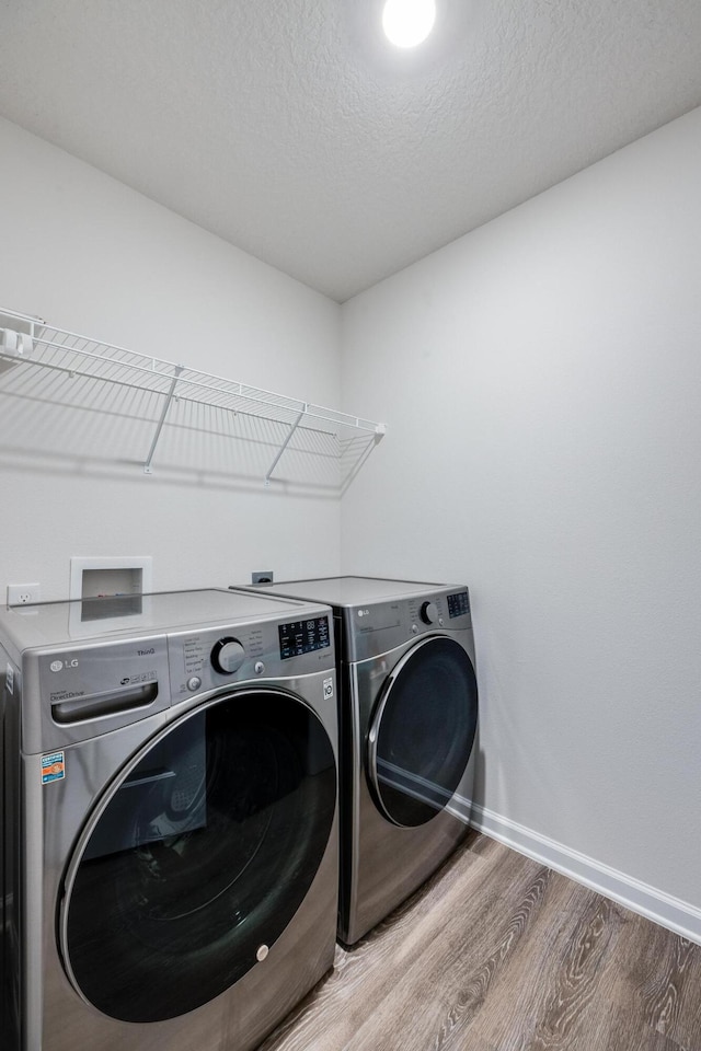 laundry area with washer and dryer, a textured ceiling, and hardwood / wood-style flooring