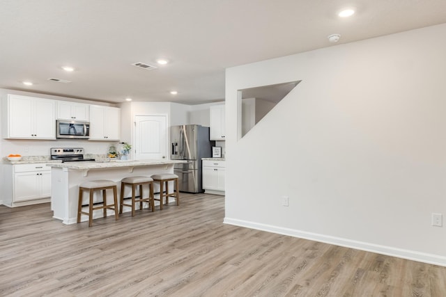 kitchen featuring white cabinets, a kitchen breakfast bar, a kitchen island, and stainless steel appliances