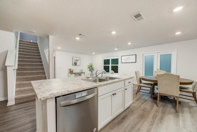 kitchen featuring white cabinetry, dishwasher, sink, an island with sink, and light hardwood / wood-style floors