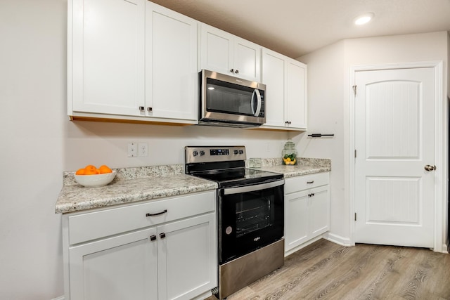 kitchen featuring light stone counters, light hardwood / wood-style flooring, white cabinets, and stainless steel appliances