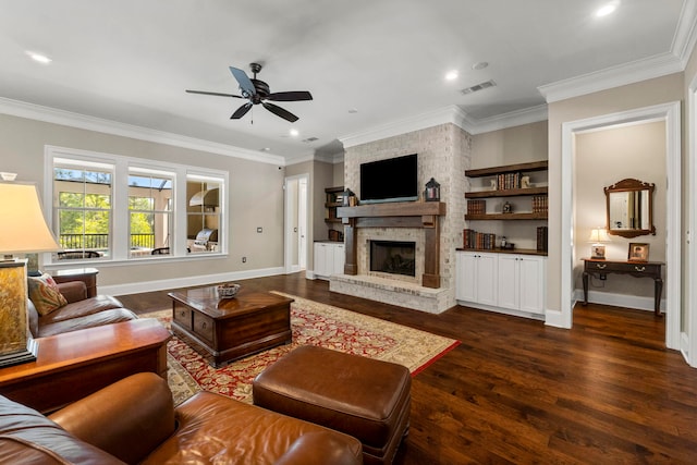 living room with a stone fireplace, crown molding, dark wood-type flooring, and ceiling fan