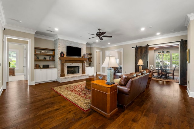 living room with plenty of natural light, a barn door, ceiling fan, and dark hardwood / wood-style floors