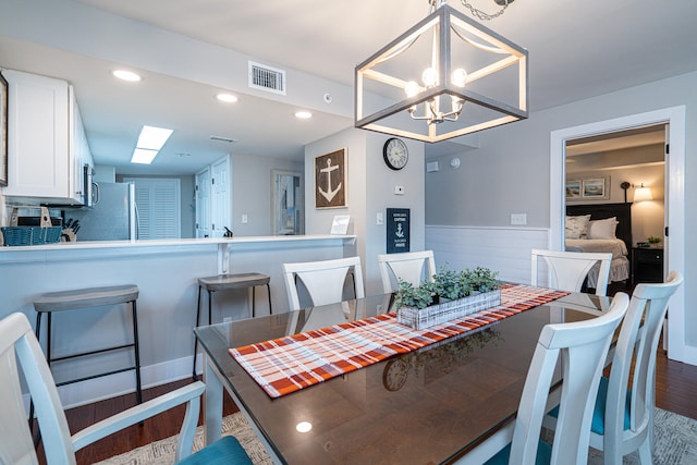 dining area featuring hardwood / wood-style floors and an inviting chandelier