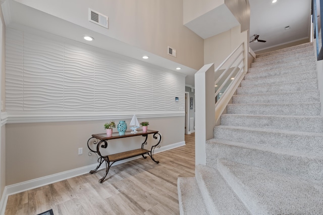 stairs featuring light hardwood / wood-style flooring and a high ceiling