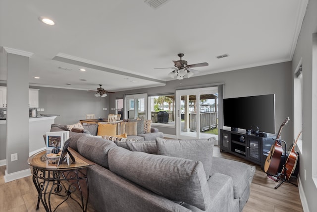 living room featuring light hardwood / wood-style flooring, crown molding, and ceiling fan